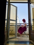 red headed woman sits on a balcony reading
